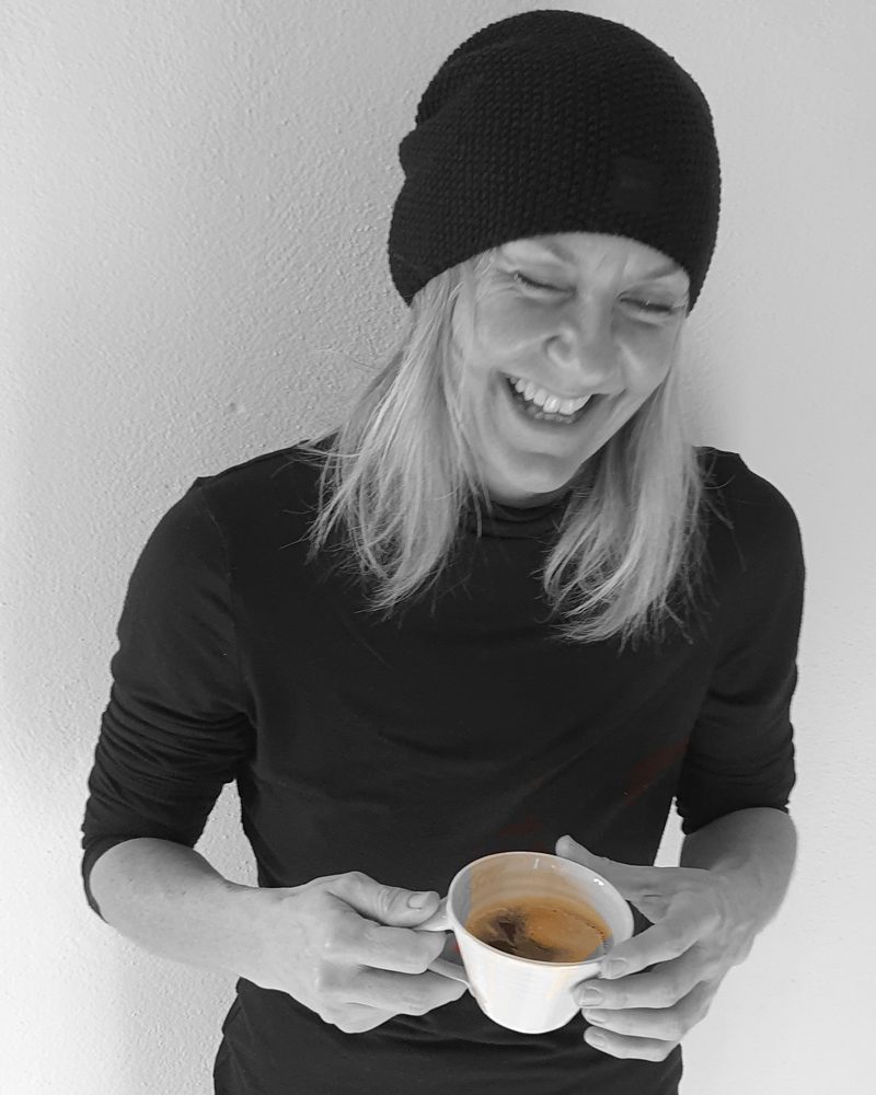 Alexandra Gauder lacht mit einer Tasse Kaffee in der Hand